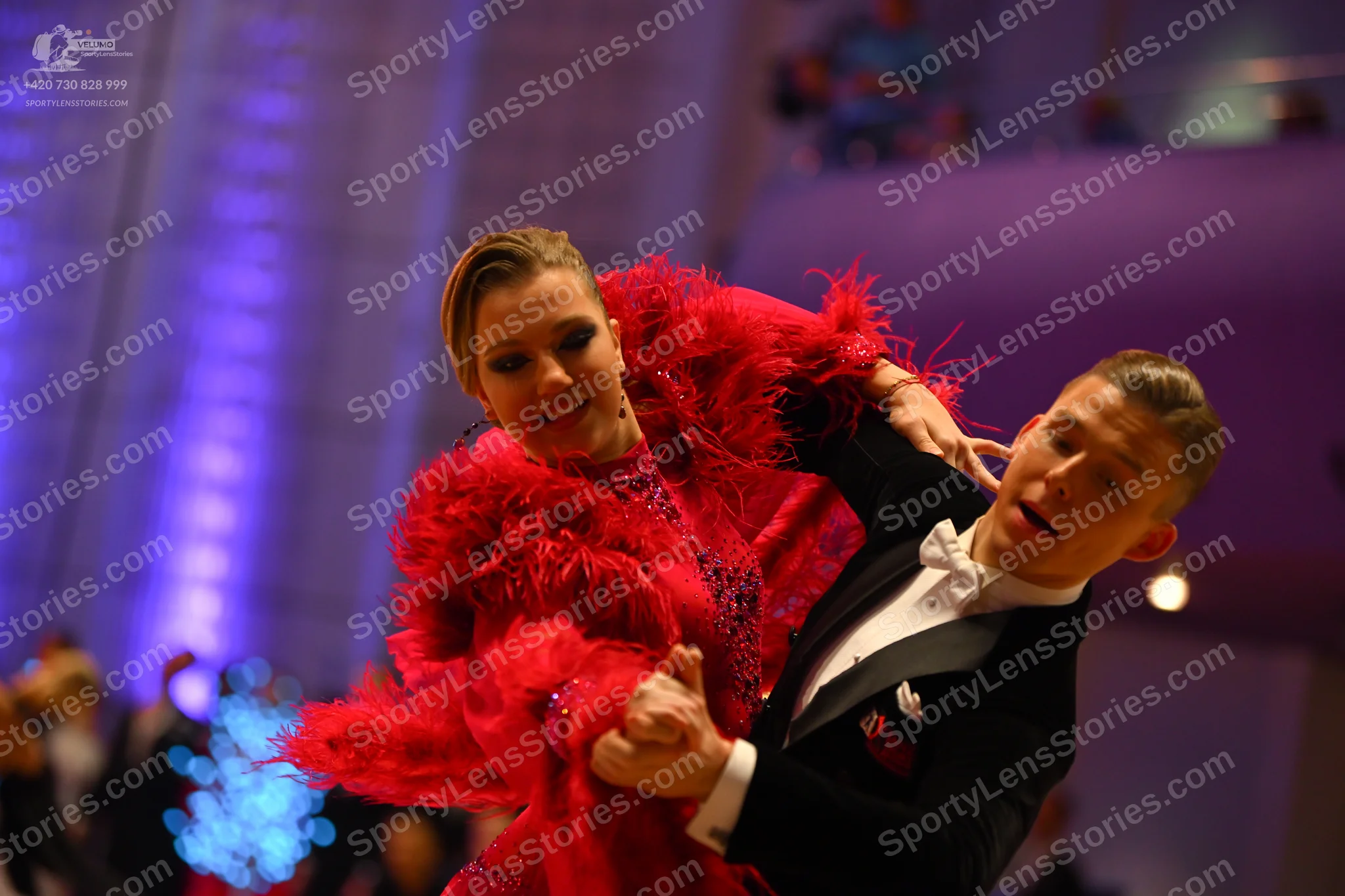 Dancesport competitor: Female dancer: red sequined Latin dress with large red feather trim