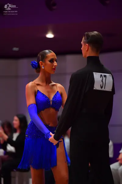 Dancesport competitor: Female dancer: blue latin dress with sequins and fringe, a matching blue long gl