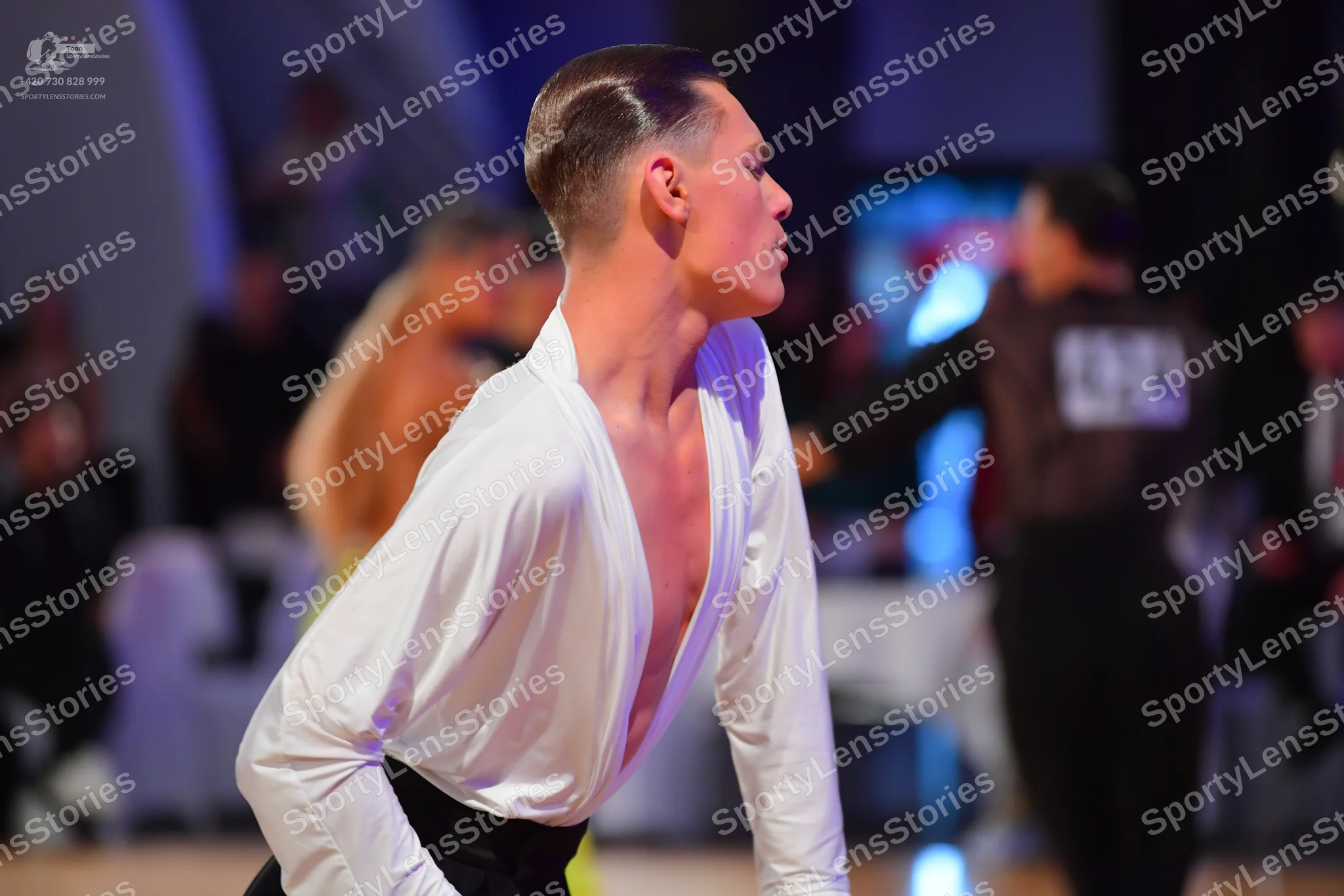 Dancesport competitor #548: Male dancer (foreground): white long-sleeved shirt with a deep V-neck and black 