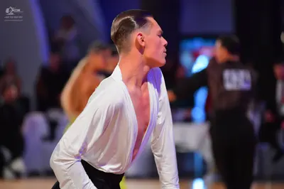 Dancesport competitor #548: Male dancer (foreground): white long-sleeved shirt with a deep V-neck and black 