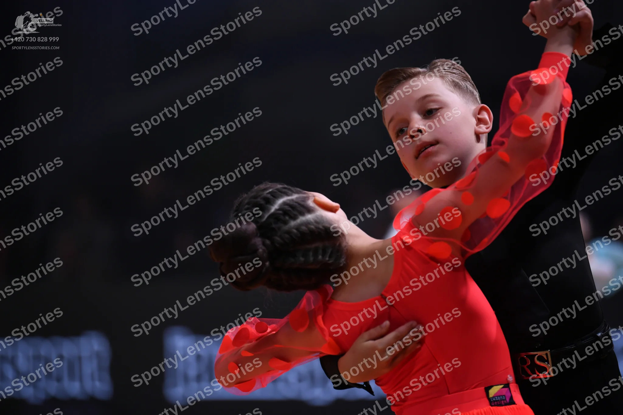 Dancesport competitor: Male dancer: black long-sleeved top with a black waistband featuring a red/pink