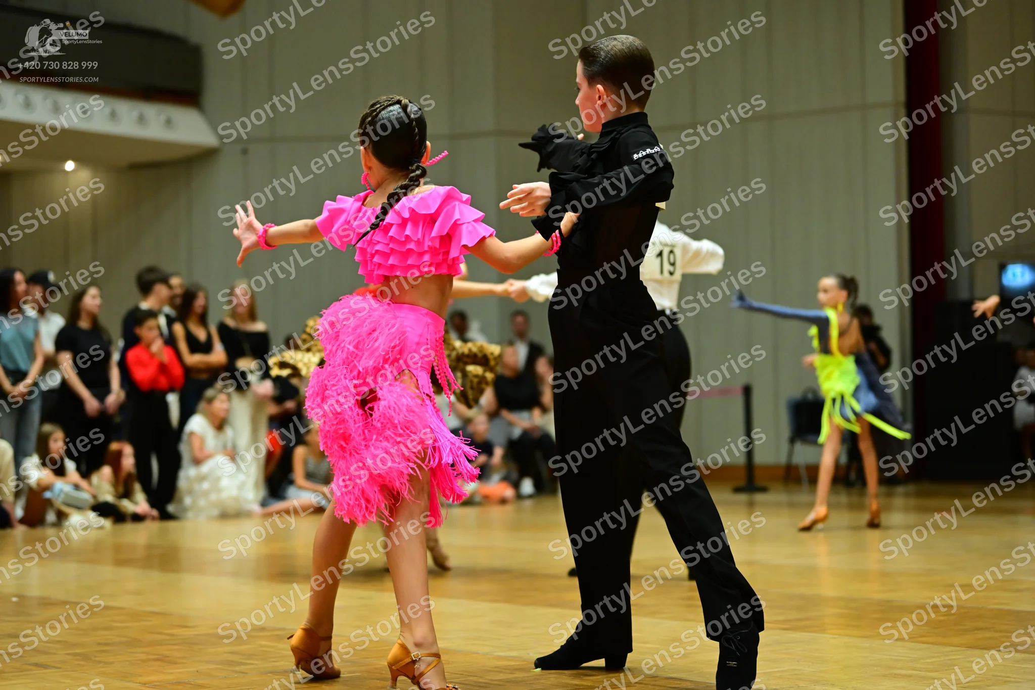 Dancesport competitor #19: Female dancer in foreground: vibrant pink Latin dance dress with ruffled sleeves