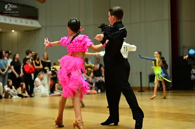 Dancesport competitor #19: Female dancer in foreground: vibrant pink Latin dance dress with ruffled sleeves
