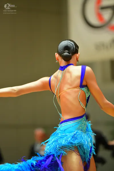 Dancesport competitor: Female dancer: blue latin dress with sequins, crystals, and long fringe; it has 
