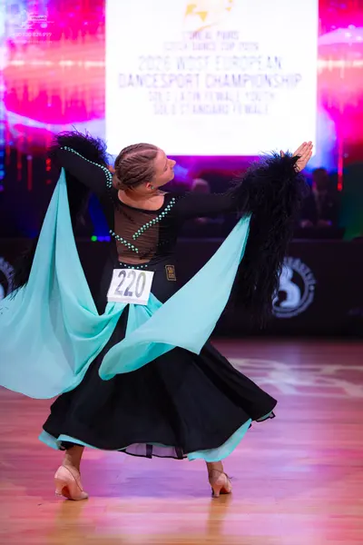 Dancesport competitor: Female dancer: black long-sleeved dance dress with large, flowing light blue pan