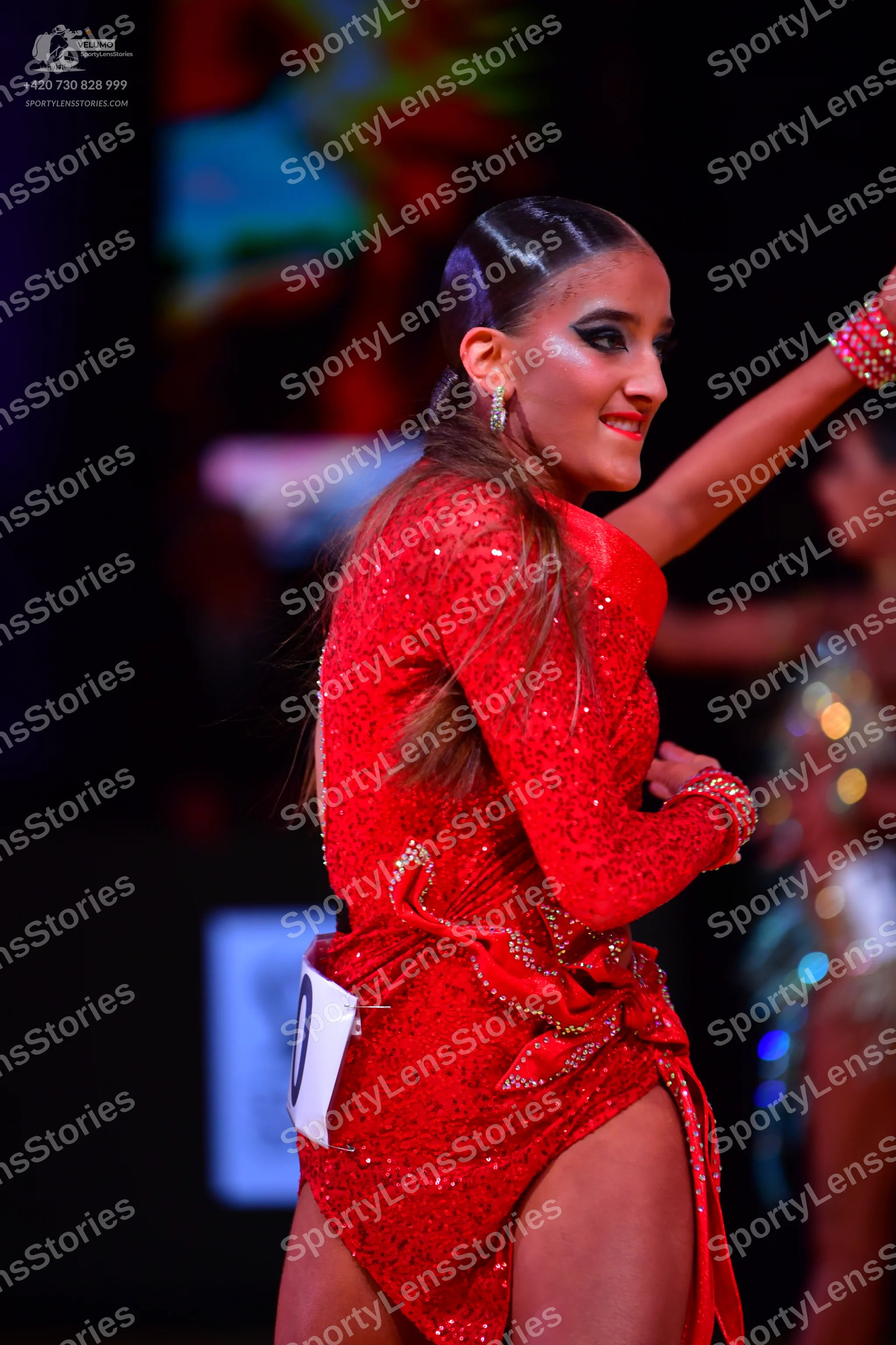 Dancesport competitor: Female dancer: red latin dress with sequins, long sleeves, and an asymmetric ski