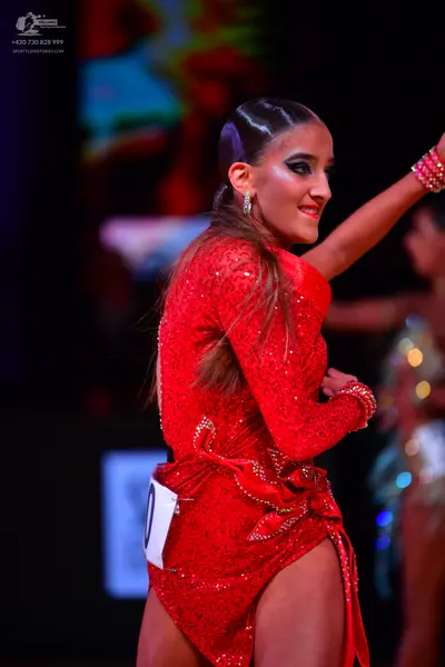 Dancesport competitor: Female dancer: red latin dress with sequins, long sleeves, and an asymmetric ski