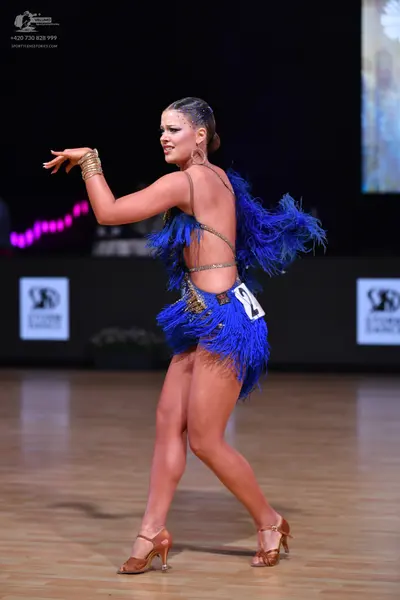 Dancesport competitor: Female dancer: blue Latin dance dress with heavy blue fringe and sequins, backle
