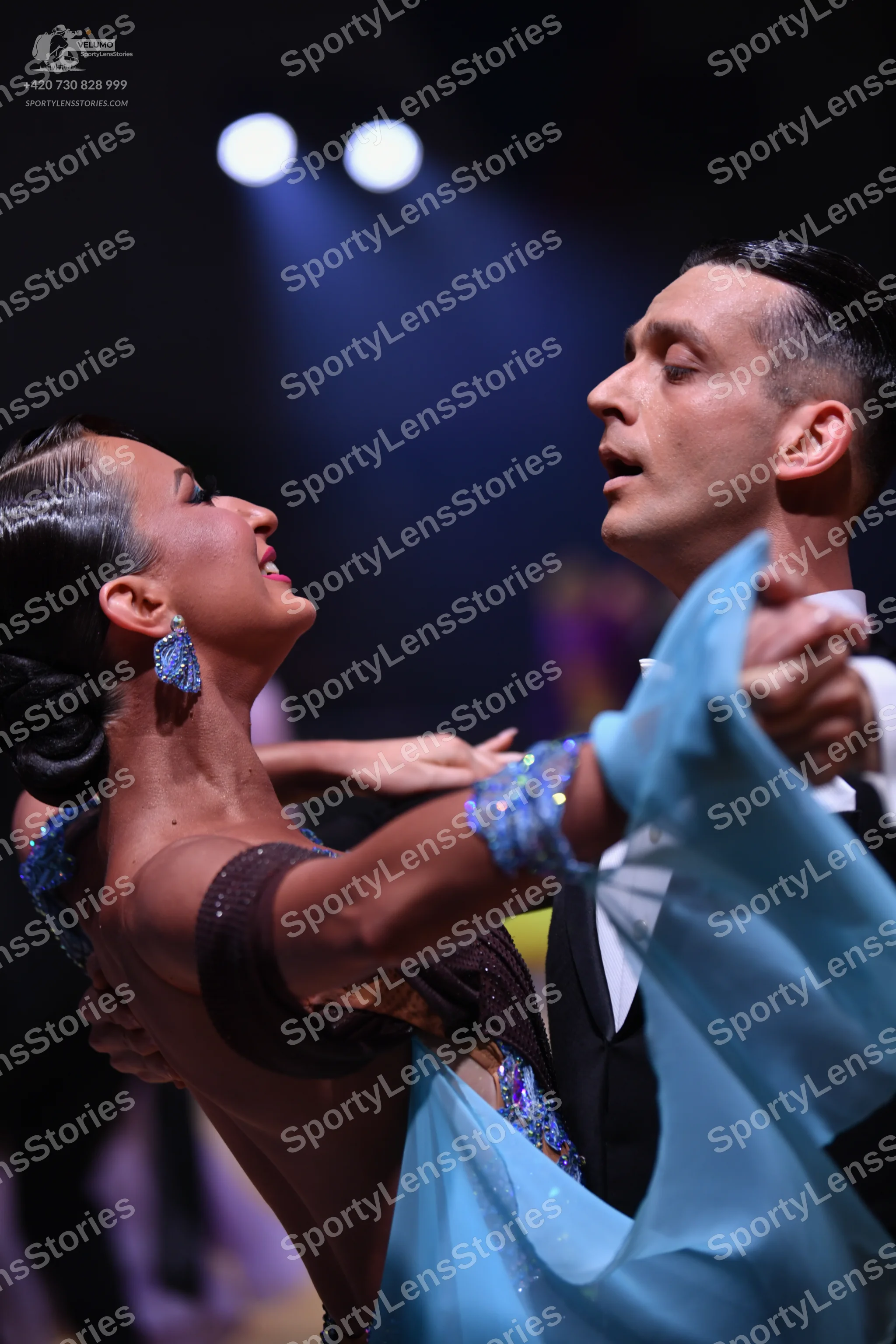 Dancesport competitor: Female dancer: dark brown Latin dress with light blue sequined embellishments an