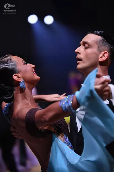 Dancesport competitor: Female dancer: dark brown Latin dress with light blue sequined embellishments an