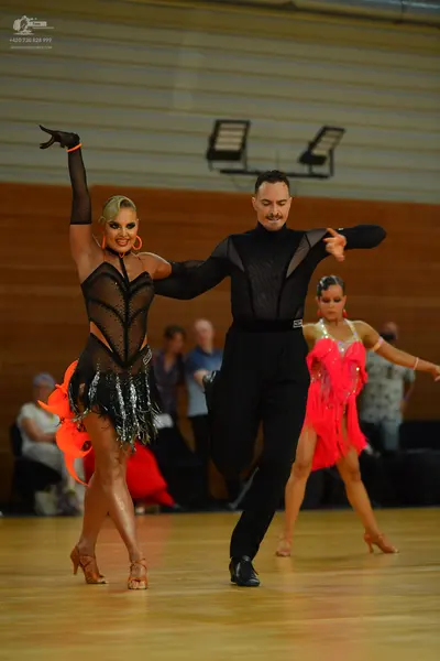 Dancesport competitor: Female dancer: black and orange latin dance dress with sheer mesh panels, black 