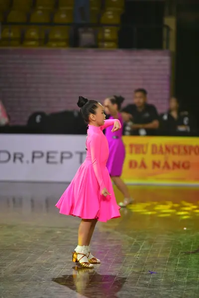 Dancesport competitor: Female dancer 1: bright pink Latin dress with a flared skirt and smooth fabric