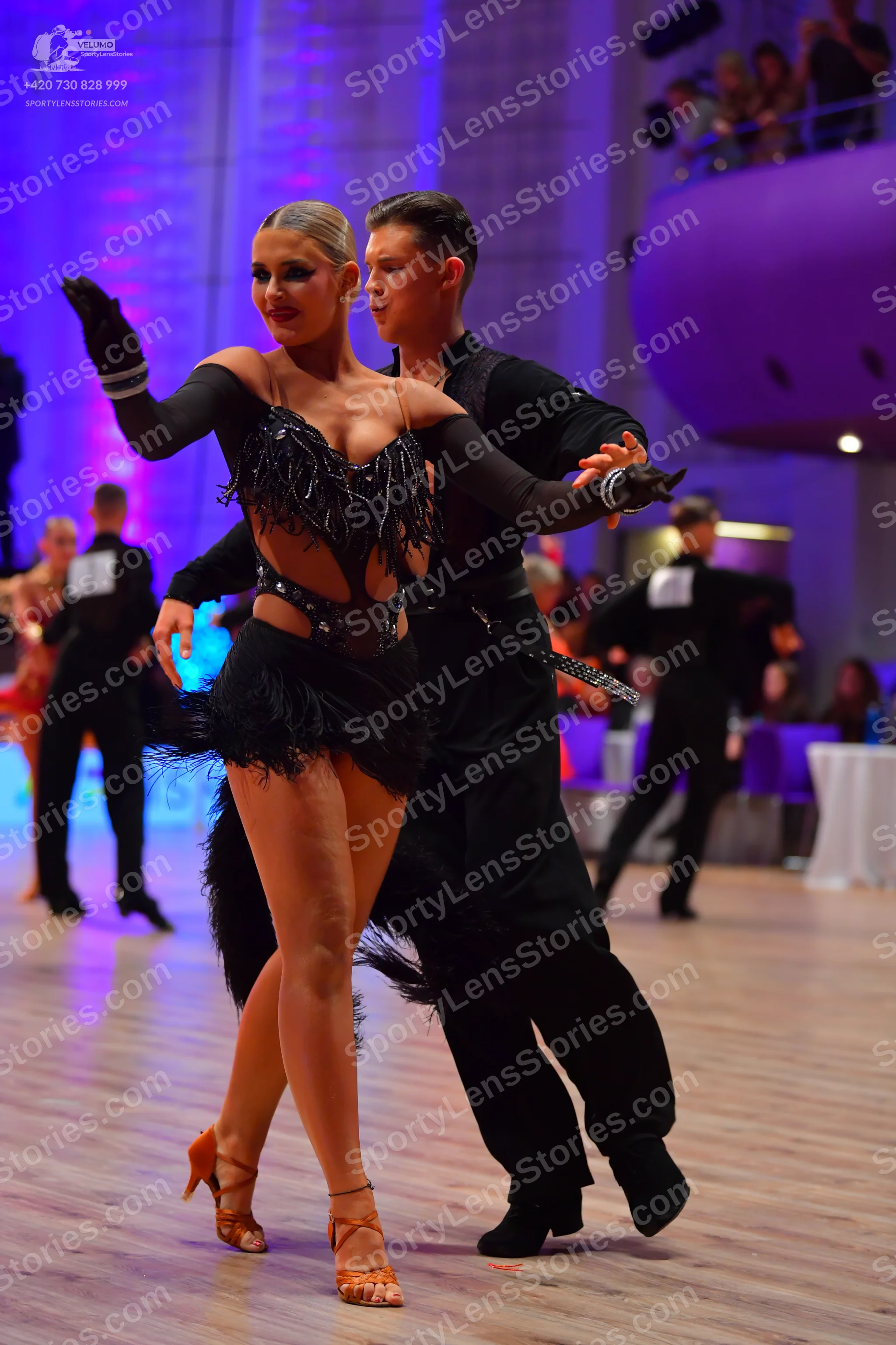 Dancesport competitor: Female dancer: black Latin dress with a sequined bodice, cutouts, and long fring