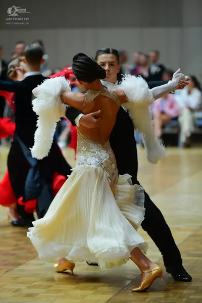Dancesport competitor: Female dancer: cream-colored ballroom dress with a sequined and lace bodice, a f