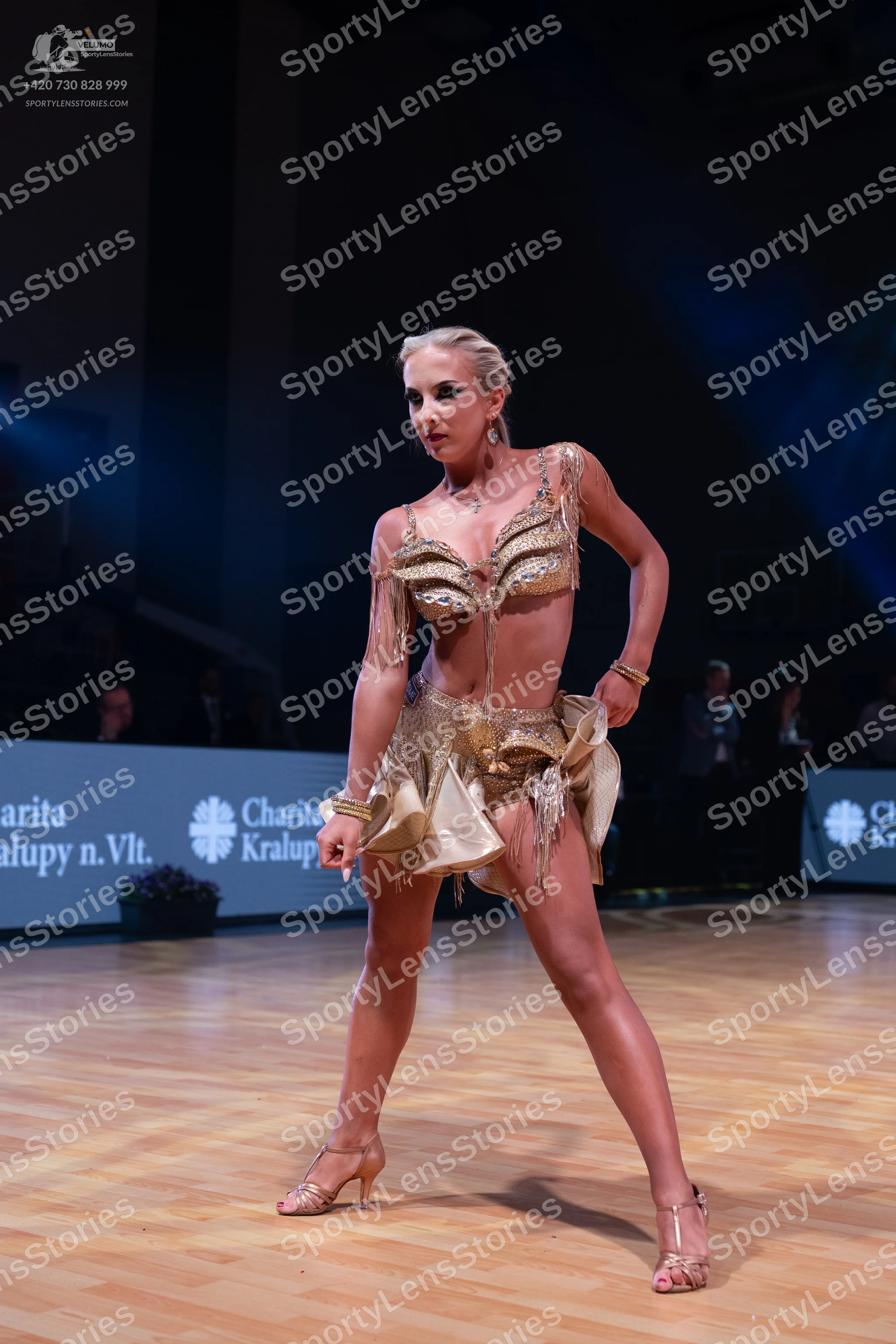 Dancesport competitor: Female dancer: gold Latin dance costume with a bra-style top and skirt, featurin