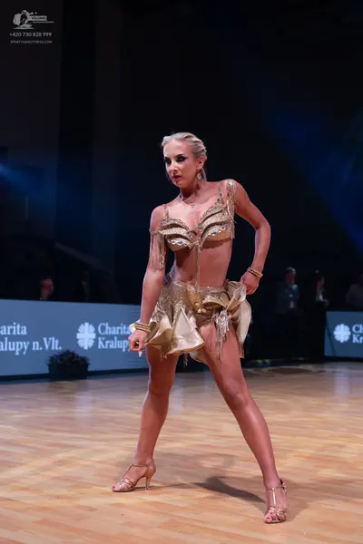 Dancesport competitor: Female dancer: gold Latin dance costume with a bra-style top and skirt, featurin