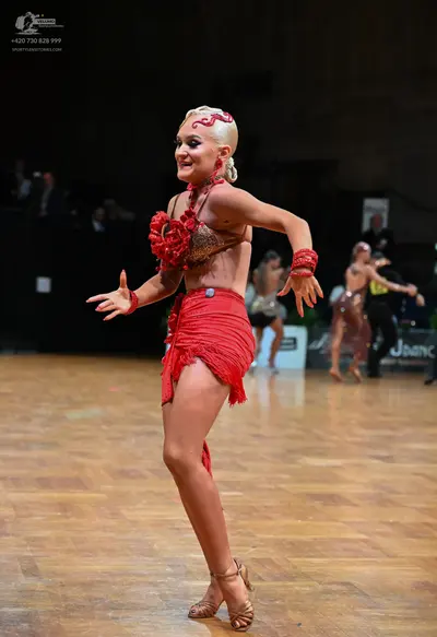 Dancesport competitor: Female dancer in foreground: red latin dress with a decorated bodice and a fring