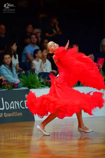 Dancesport competitor: Female dancer: red Latin dress with voluminous ruffled/fringed skirt and silver 