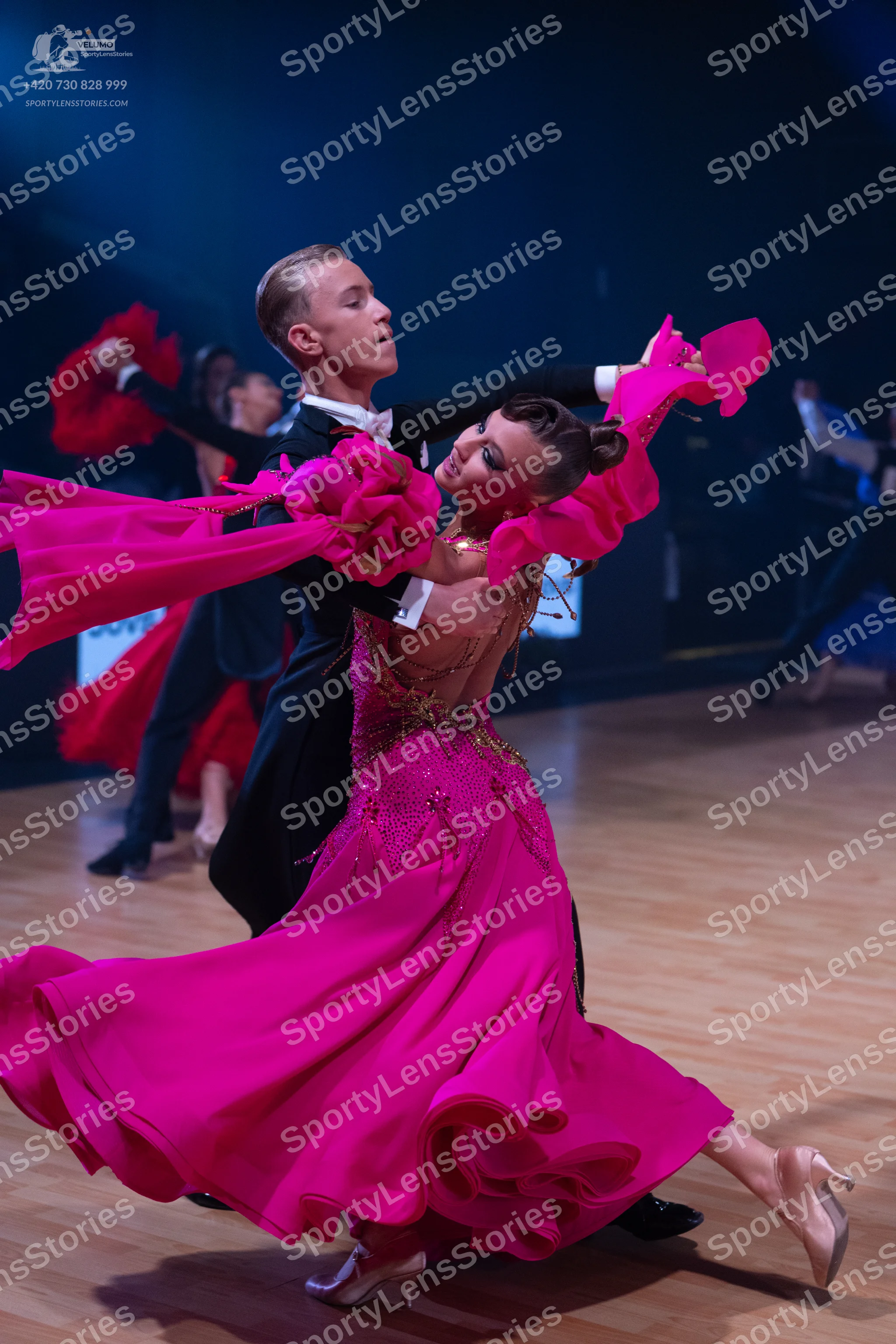 Dancesport competitor: Main female dancer: bright pink ballroom gown with a voluminous, ruffled skirt a