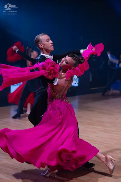 Dancesport competitor: Main female dancer: bright pink ballroom gown with a voluminous, ruffled skirt a