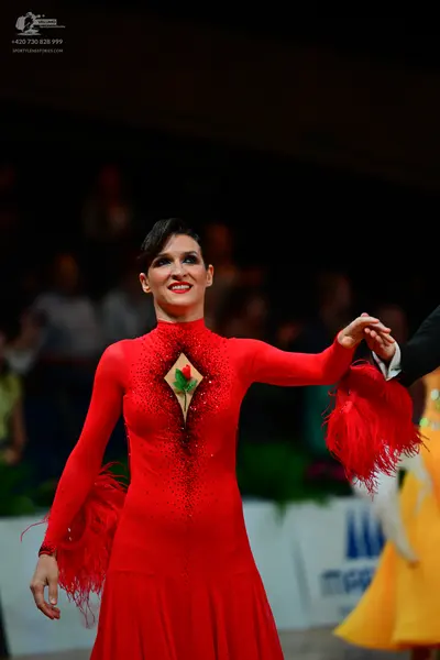 Dancesport competitor: Female dancer: red long-sleeved Latin dress with red fringe on the cuffs, red se