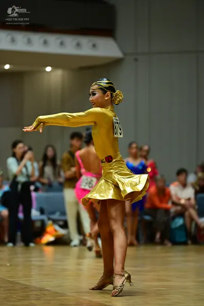 Dancesport competitor #879: Female dancer: gold metallic long-sleeved latin dress with a flared skirt, gold 