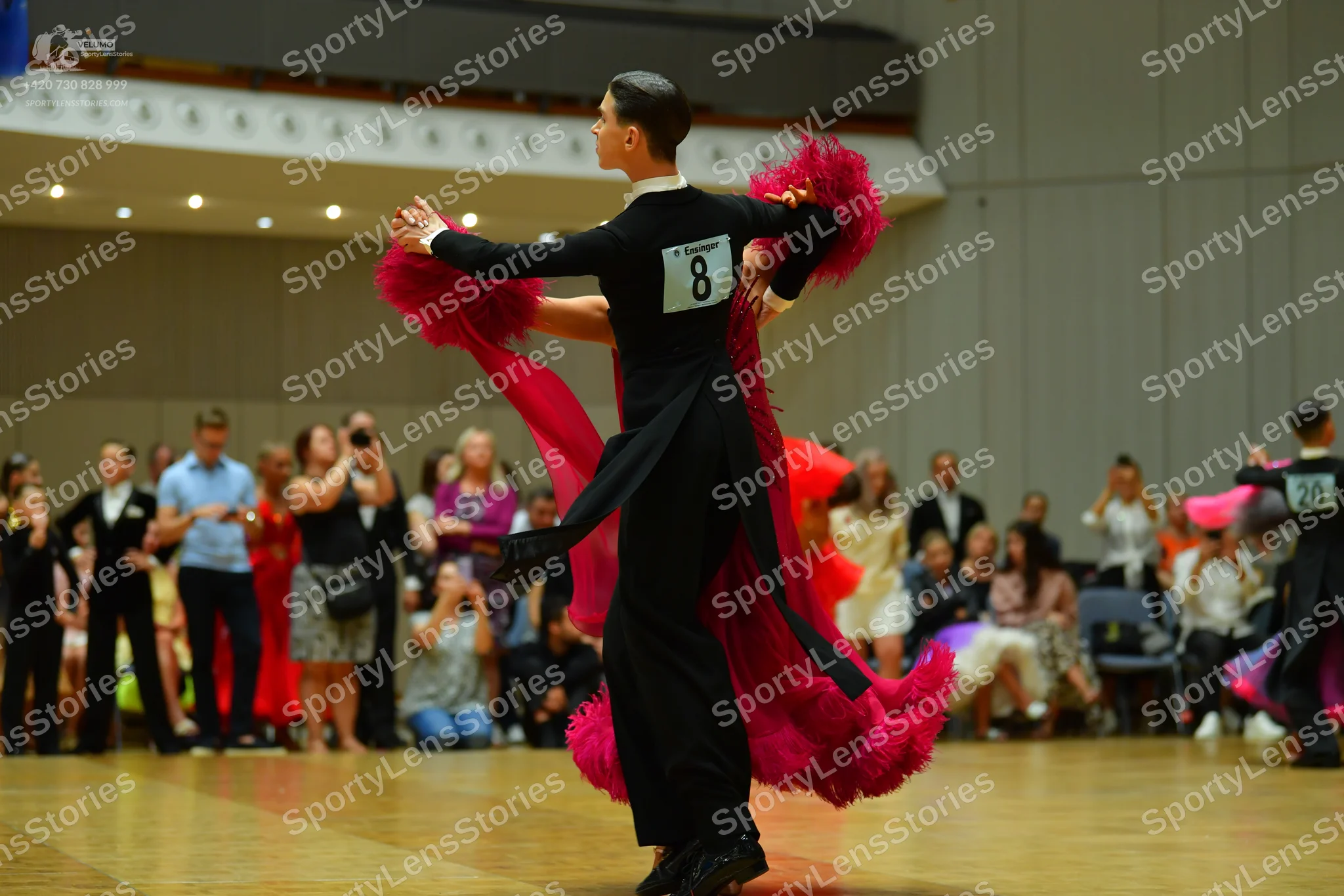 Dancesport competitor: Male dancer: black long-sleeved top with a white collar and black trousers, feat