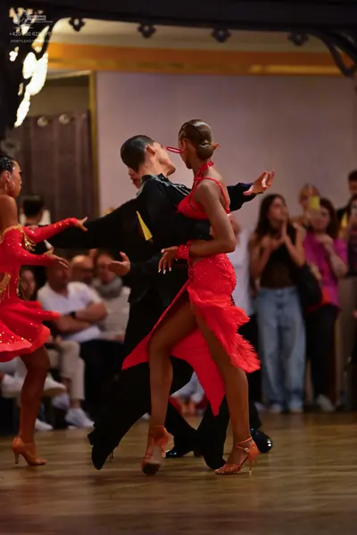 Dancesport competitor: Female dancer (left): red latin dress with gold sequins