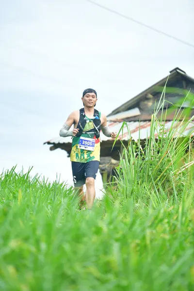 Marathon runner #5028: Runner 1: dark green patterned jersey, dark blue shorts, black cap, white socks,