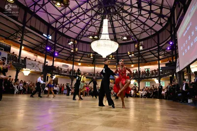 Dancesport competitor: Male dancer in foreground: black long-sleeve shirt and black trousers