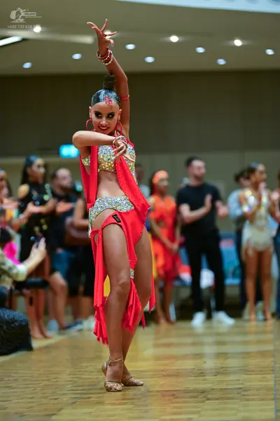 Dancesport competitor: Main female dancer: red Latin dance costume featuring a silver and gold sequined