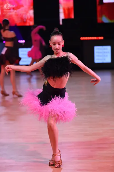 Dancesport competitor: Female dancer: black latin dress with a large pink feathered skirt and a black f