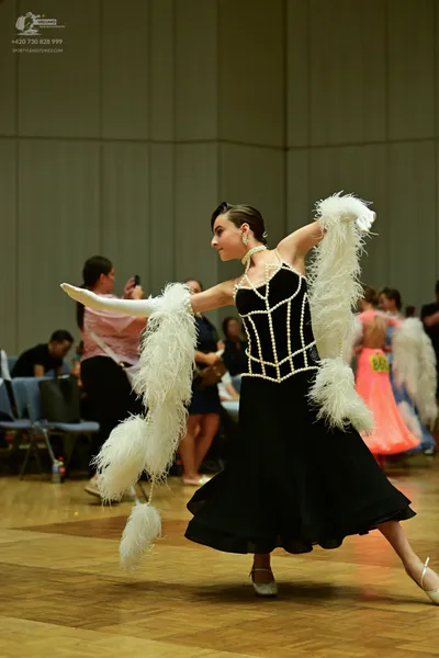Dancesport competitor: ** Black fitted gown with a corset-style bodice and a dramatic, high-low skirt