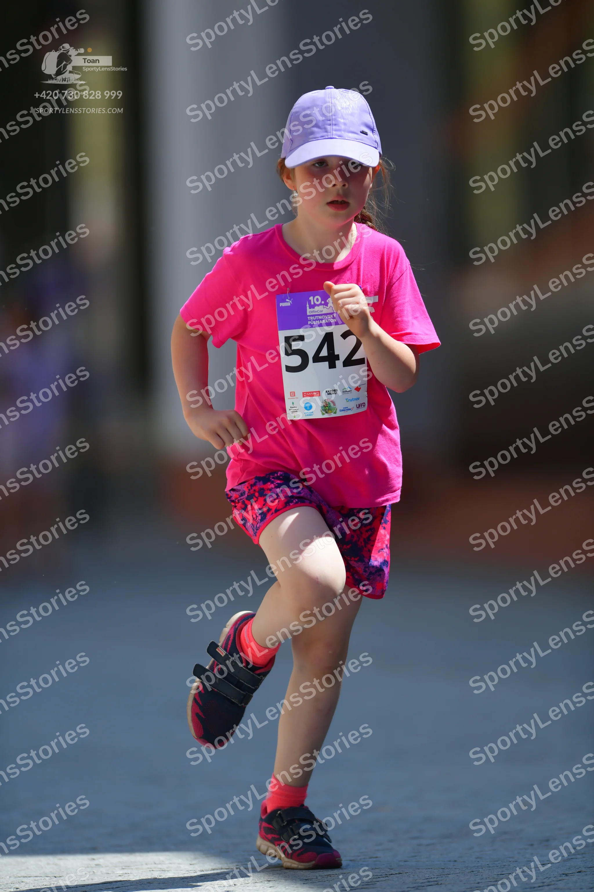 Marathon runner #542: Runner 1: pink t-shirt, pink and blue patterned shorts, black shoes with pink so