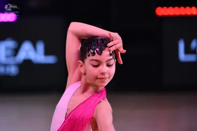 Dancesport competitor: Female dancer: bright pink asymmetrical dance top with fine vertical texture and
