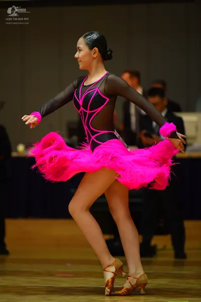 Dancesport competitor: Female dancer: black Latin dress with bright pink/magenta trim and mesh panels, 