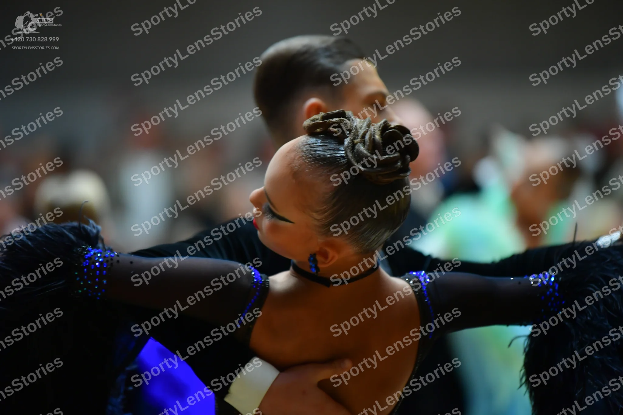 Dancesport competitor: Female dancer: black latin dress with blue/purple sequins on the shoulders and b