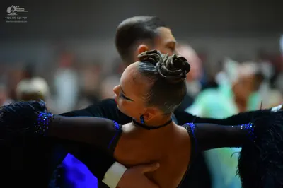 Dancesport competitor: Female dancer: black latin dress with blue/purple sequins on the shoulders and b