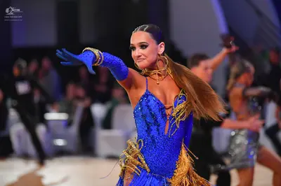 Dancesport competitor: Main female dancer: blue sequined Latin dress with gold fringe, matching long bl