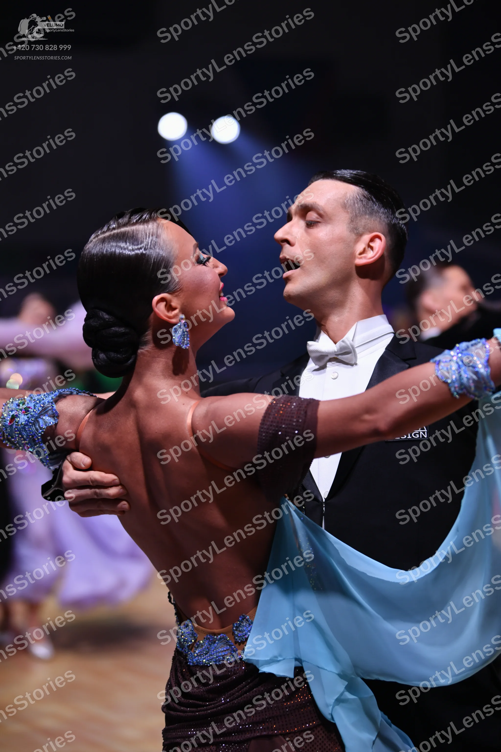 Dancesport competitor: Female dancer: backless dark brown latin dress with blue sequined patterns and l