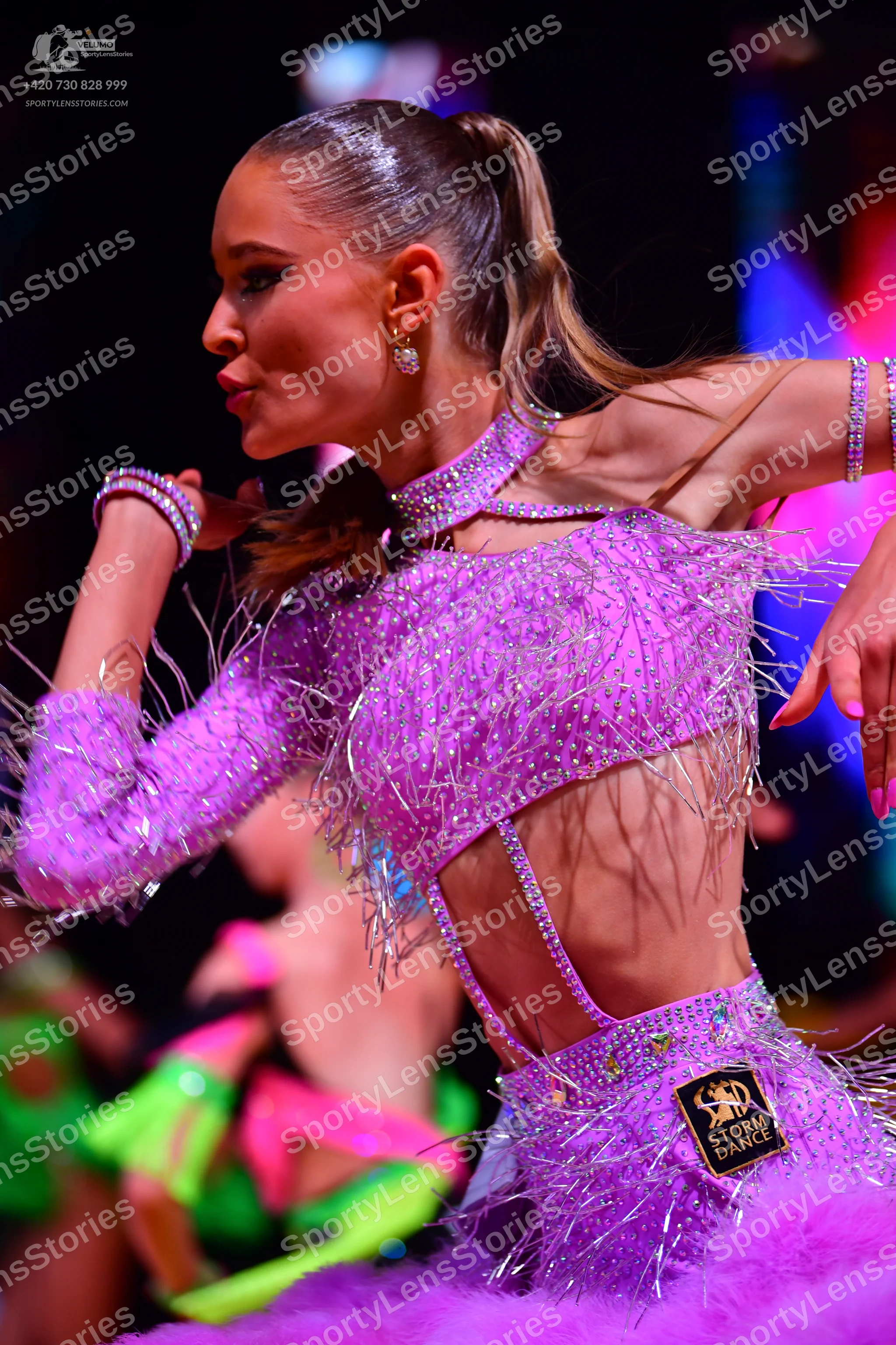 Dancesport competitor: Female dancer in foreground: lavender Latin dance dress with heavy sequin embell