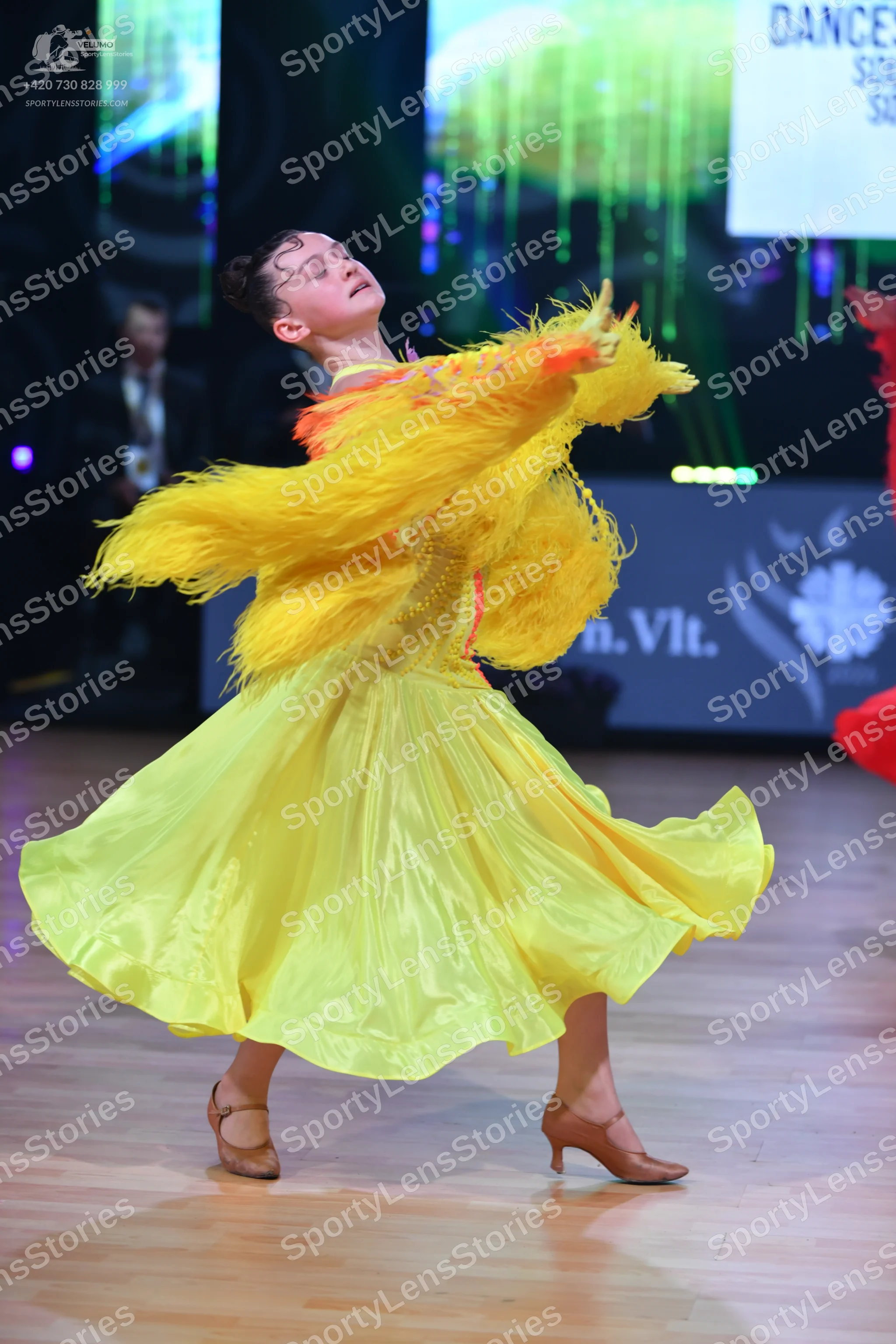 Dancesport competitor: Female dancer: bright yellow long-sleeved ballroom dress with a large, flowing s