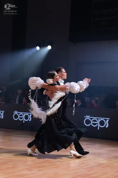 Dancesport competitor: Female dancer: black ballroom dress with voluminous white puffy sleeves adorned 
