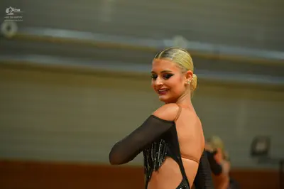 Dancesport competitor: Female dancer: black latin dress with sheer sleeves and black fringe