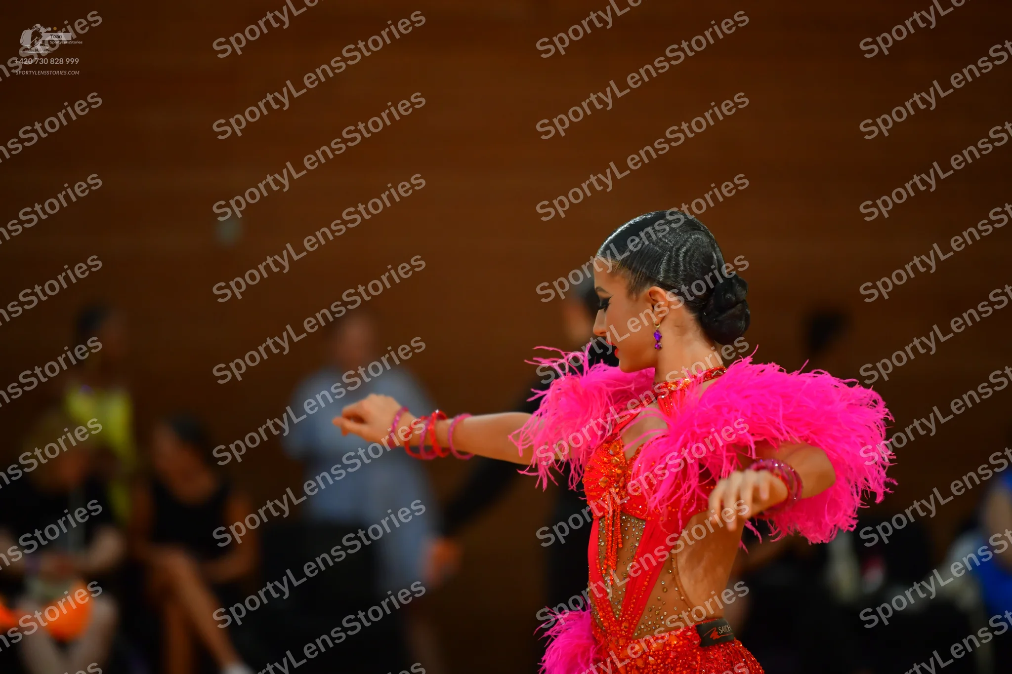 Dancesport competitor: Red latin dress with a plunging V-neckline, sheer long sleeves, and a dramatic, 