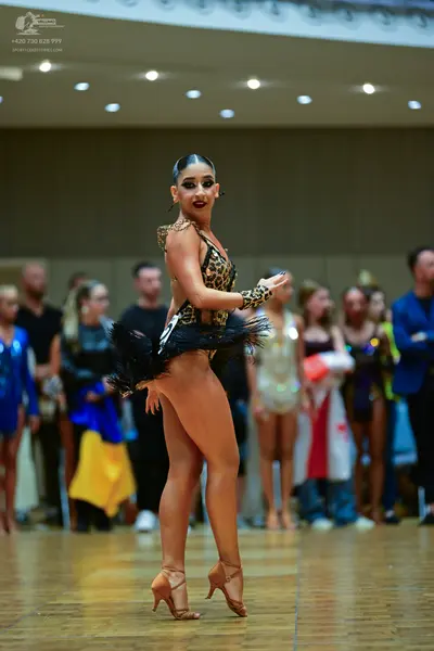 Dancesport competitor: Female dancer: leopard print latin bodysuit with black feather trim and nude-col