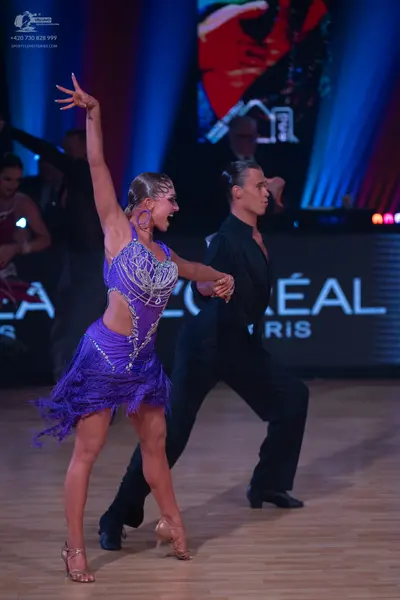 Dancesport competitor: Female dancer: purple Latin dress with silver sequin embellishments, side cut-ou