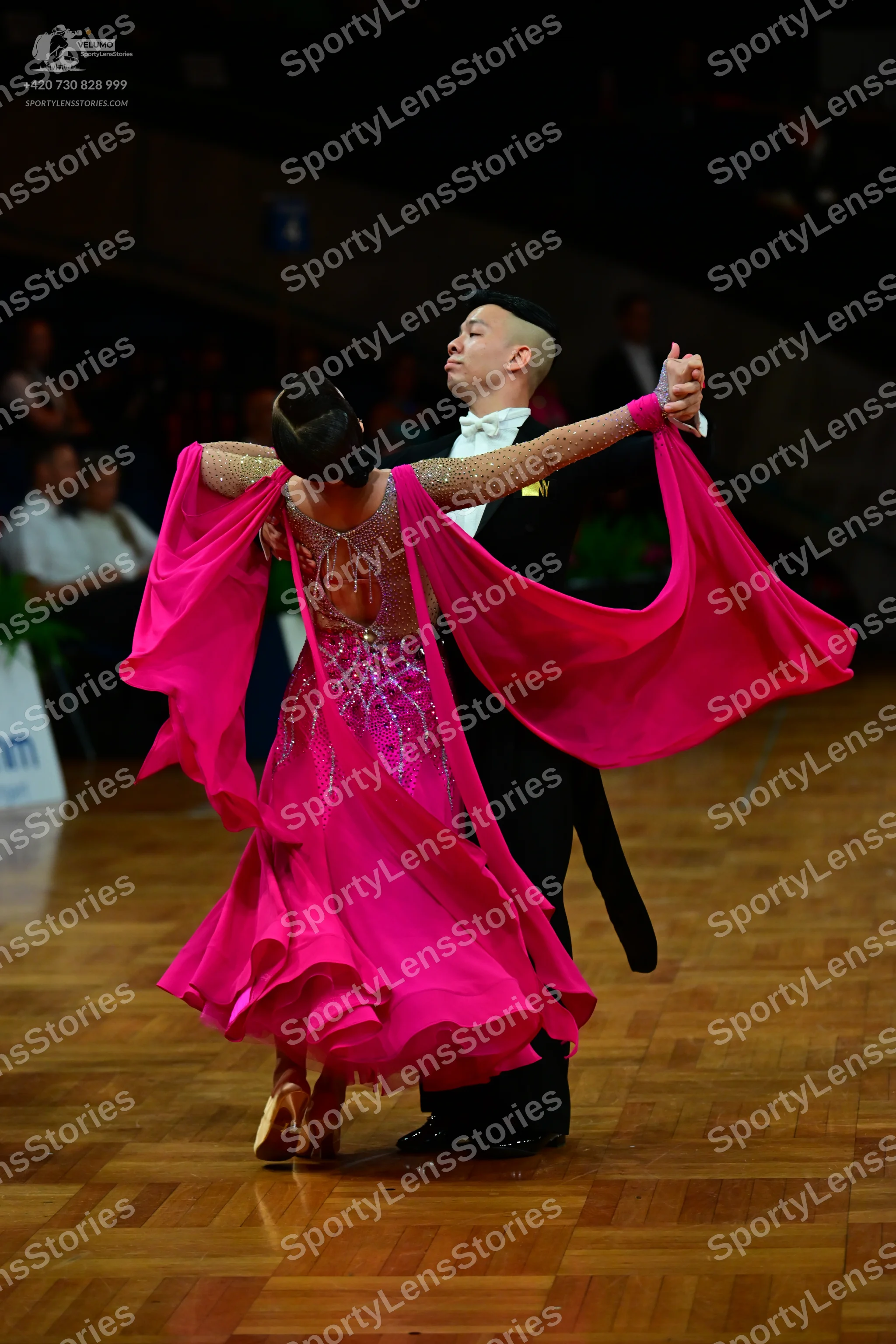 Dancesport competitor: Female dancer: vibrant pink ballroom gown with a voluminous, flowing skirt and l