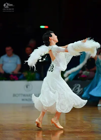 Dancesport competitor: Female dancer: white lace ballroom dress with long sleeves, a voluminous skirt, 