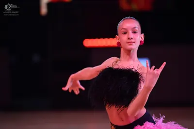 Dancesport competitor: Female dancer: black top with black feather-like texture, black waistband, and a